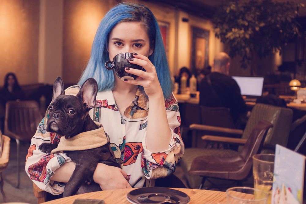 young woman drinking coffee holding her dog